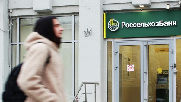 Прохожий около входа в офис банка Россельхозбанк на одной из улиц в Москве