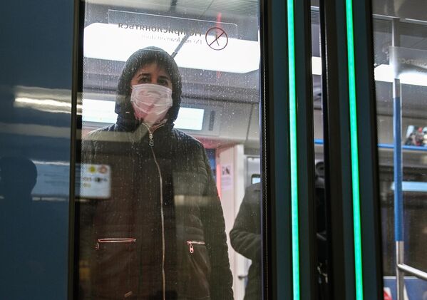 Женщина в защитной маске в вагоне поезда на станции метро Новокузнецкая в Москве Женщина в защитной маске в вагоне поезда на станции метро Новокузнецкая в Москве
