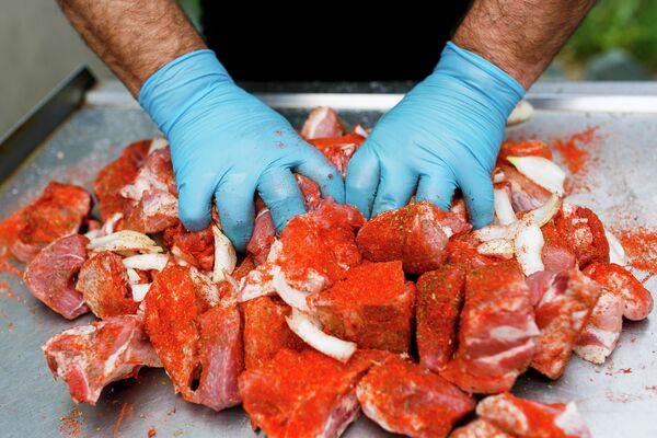 Мужчина маринует мясо в луке и аджике Мужчина маринует мясо в луке и аджике
