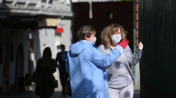 Женщины в медицинских масках и перчатках на одной из улиц в Москве Женщины в медицинских масках и перчатках на одной из улиц в Москве