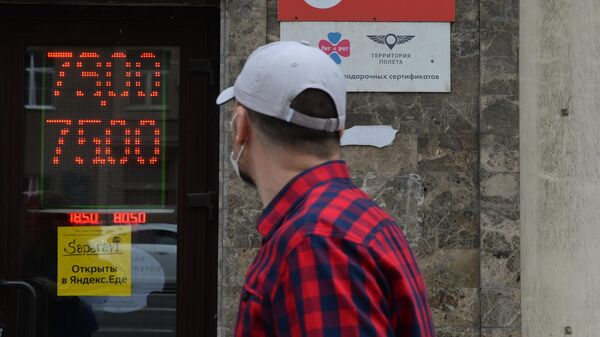 Мужчина в защитной маске у информационного табло с курсом валют на Тверской улице в Москве Мужчина в защитной маске у информационного табло с курсом валют на Тверской улице в Москве
