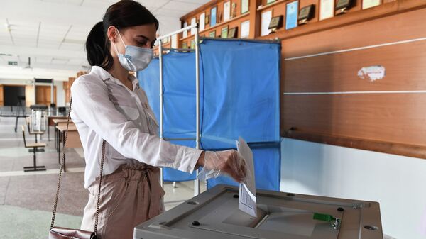 Девушка опускает бюллетень в урну во время демонстрации работы модельного участка для общероссийского голосования по поправкам в Конституцию РФ Девушка опускает бюллетень в урну во время демонстрации работы модельного участка для общероссийского голосования по поправкам в Конституцию РФ