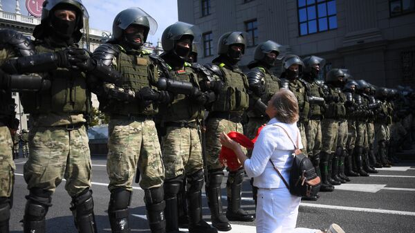 Участница акции протеста и сотрудники правоохранительных органов на проспекте Независимости в Минске Участница акции протеста и сотрудники правоохранительных органов на проспекте Независимости в Минске
