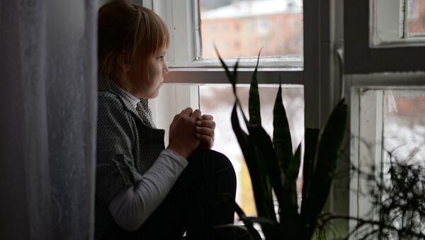 Девочка сидит у окна в детском доме. Архивное фото Девочка сидит у окна в детском доме. Архивное фото