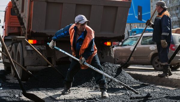 Рабочий разравнивает асфальт во время ремонта дорожного покрытия на улице Кирова в Омске Рабочий разравнивает асфальт во время ремонта дорожного покрытия на улице Кирова в Омске