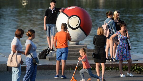 Прохожие рядом с гигантским покеболом из компьютерной игры Pokemon Go от компании Nintendo на набережной городского пруда в Екатеринбуре Прохожие рядом с гигантским покеболом из компьютерной игры Pokemon Go от компании Nintendo на набережной городского пруда в Екатеринбуре