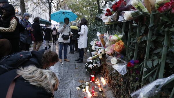 Люди приносят цветы и зажигают свечи у входа в клуб Bataclan в Париже Люди приносят цветы и зажигают свечи у входа в клуб Bataclan в Париже