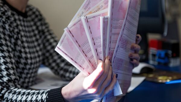 Сотрудник страховой компании демонстрирует страховой полис ОСАГО Сотрудник страховой компании демонстрирует страховой полис ОСАГО