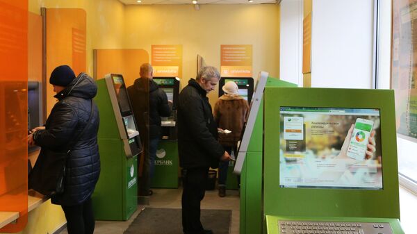 Посетители в зале банкоматов в отделении Сбербанка. Архивное фото Посетители в зале банкоматов в отделении Сбербанка. Архивное фото