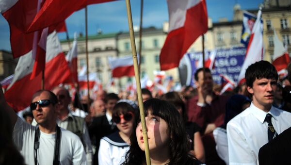 Жители Кракова с польскими флагами на площади города. Архивное фото Жители Кракова с польскими флагами на площади города. Архивное фото