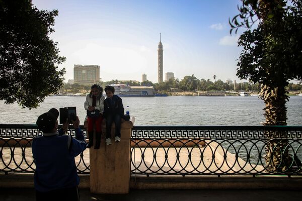Дети фотографируются на набережной в Каире. На дальнем плане: Каирская телебашня Дети фотографируются на набережной в Каире. На дальнем плане: Каирская телебашня