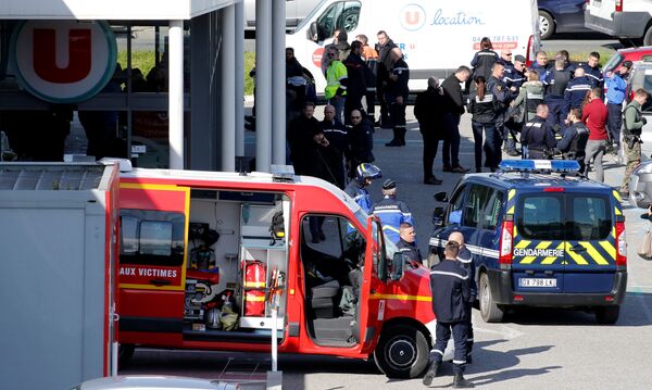 Сотрудники полиции у супермаркета в коммуне Треб на юге Франции, где произошел захват заложников. 23 марта 2018 Сотрудники полиции у супермаркета в коммуне Треб на юге Франции, где произошел захват заложников. 23 марта 2018