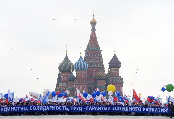 Участники первомайской демонстрации несут плакат Единство, солидарность, труд - гарантия успешного развития на Красной площади в Москве Участники первомайской демонстрации несут плакат Единство, солидарность, труд - гарантия успешного развития на Красной площади в Москве