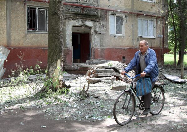 Мужчина едет на велосипеде во дворе жилого дома, пострадавшего в результате обстрела, в поселке Горловка Донецкой области Мужчина едет на велосипеде во дворе жилого дома, пострадавшего в результате обстрела, в поселке Горловка Донецкой области
