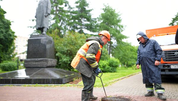 Сотрудники ГУП Мосводосток проверяют смотровой колодец Сотрудники ГУП Мосводосток проверяют смотровой колодец