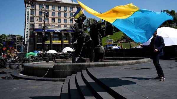 Мужчина с украинским флагом у памятника основателям Киева на площади Независимости