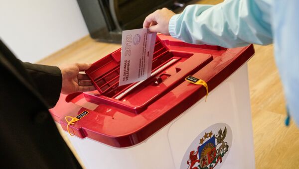 Избиратель опускает бюллетень в урну во время парламентских выборов в Латвии Избиратель опускает бюллетень в урну во время парламентских выборов в Латвии