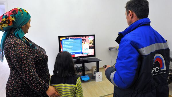 Инженер настраивает приставку цифрового телевидения в одном из жилых домов в Гудермесе