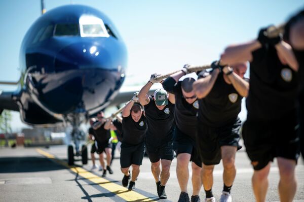 Мужчины тянут самолет JetBlue A320 во время ежегодных соревнований Plane Pull в Международном аэропорту Джона Ф. Кеннеди Мужчины тянут самолет JetBlue A320 во время ежегодных соревнований Plane Pull в Международном аэропорту Джона Ф. Кеннеди