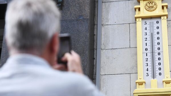 Мужчина фотографирует термометр на здании Государственной Думы РФ в Москве
