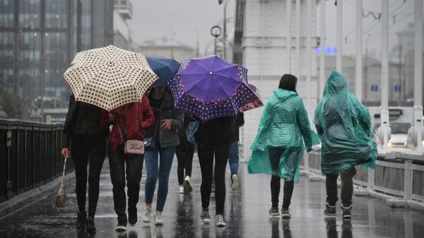Пешеходы идут по Крымскому мосту во время дождя в Москве