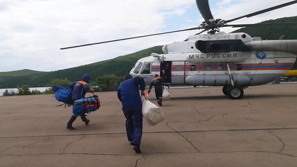 Сотрудники МЧС направляются к вертолету для облета подтопленных территорий в Иркутской области