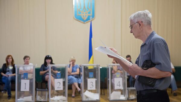 Избиратель изучает бюллетень на участке в Киеве, перед тем как проголосовать на досрочных выборах в Верховную раду Украины