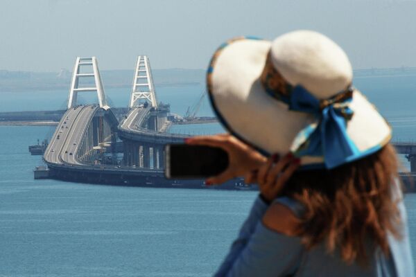 Девушка фотографирует Крымский мост через Керченский пролив Девушка фотографирует Крымский мост через Керченский пролив