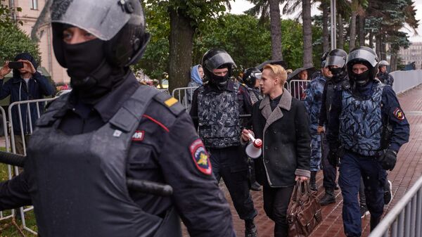 Сотрудники полиции и участник митинга за честные выборы на площади Ленина в Санкт-Петербурге. 3 августа 2019