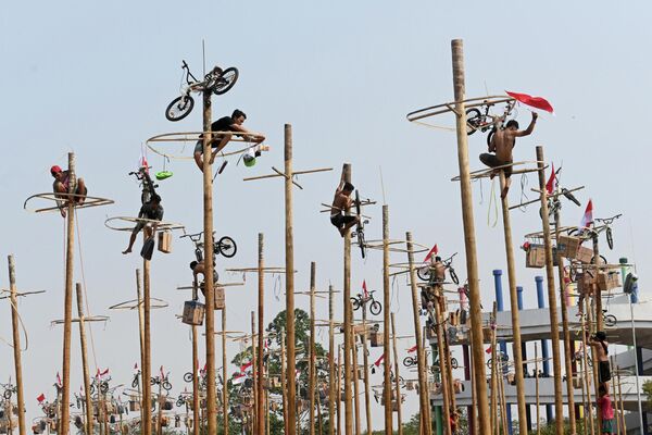Участники поднимаются на столбы во время Panjat Pinang на пляже в Джакарте Участники поднимаются на столбы во время Panjat Pinang на пляже в Джакарте