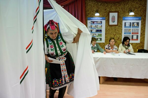 Женщина в традиционной одежде выходит из кабины для голосования, Венгрия. Женщина в традиционной одежде выходит из кабины для голосования, Венгрия.