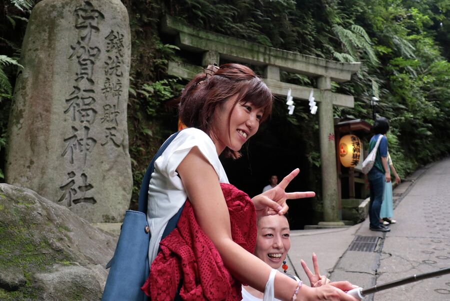 Посетители делают селфи перед храмом Зениарай Бентен. Токио, Япония