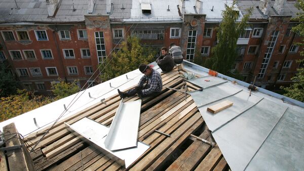 Рабочие перекрывают крышу многоэтажного дома