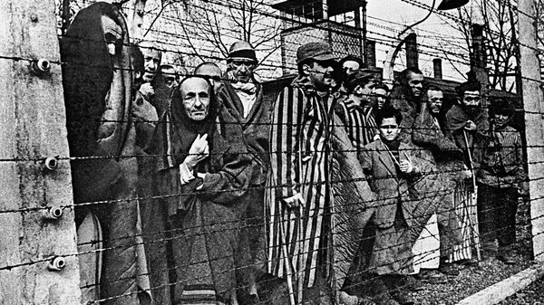 Заключенные концлагеря Освенцим смотрят в объектив из-за колючей проволоки Заключенные концлагеря Освенцим смотрят в объектив из-за колючей проволоки