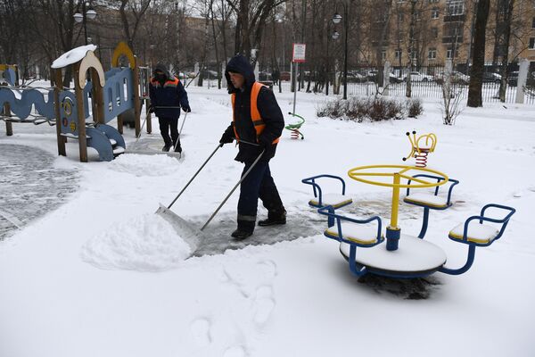 Сотрудники коммунальной службы чистят детскую площадку от снега в Москве Сотрудники коммунальной службы чистят детскую площадку от снега в Москве