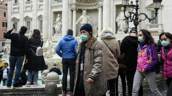 Туристы в респираторных масках возле фонтана Треви в центре Рима Туристы в респираторных масках возле фонтана Треви в центре Рима