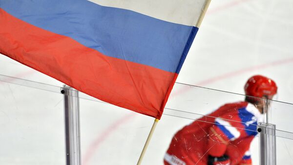 Болельщик сборной России держит флаг во время хоккейного матча
